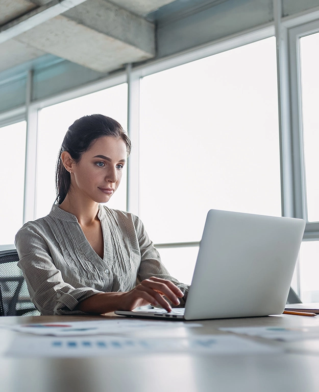 Eine Junge Frau sitzt im Büro vor ihrem Laptop