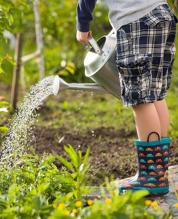 a young child is watering plants