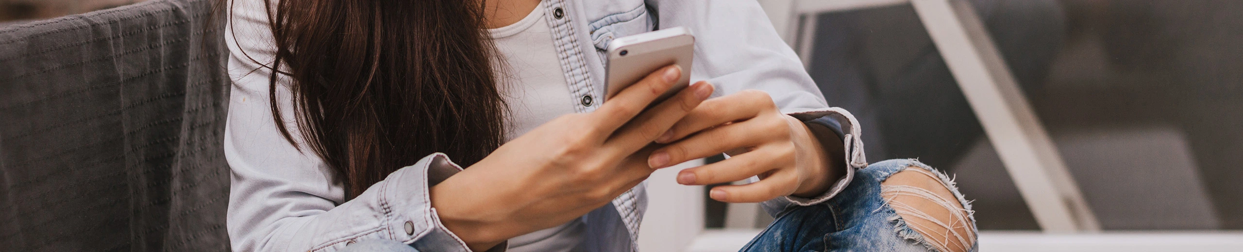 Eine junge Frau hält ihr Handy in der Hand