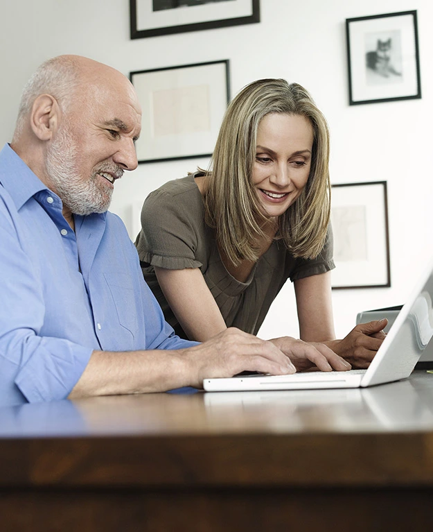 Ein alter Mann und eine junge Frau gemeinsam vor dem Laptop