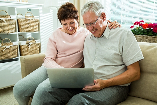 Älterer Mann und Frau sitzen vor dem Laptop