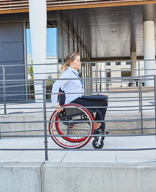 Eine Frau fährt mit dem Rollstuhl über eine Betonrampe