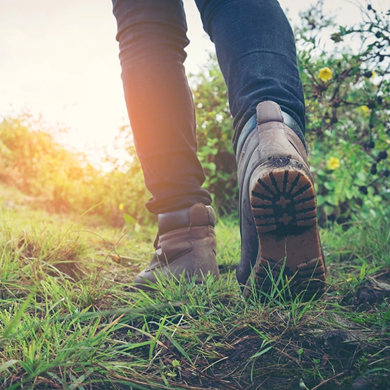 eine Person mit Wanderschuhe, die im Gras gehen