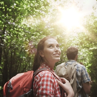 Eine Frau und ein Mann wandern im Sonnenschein durch den Wald