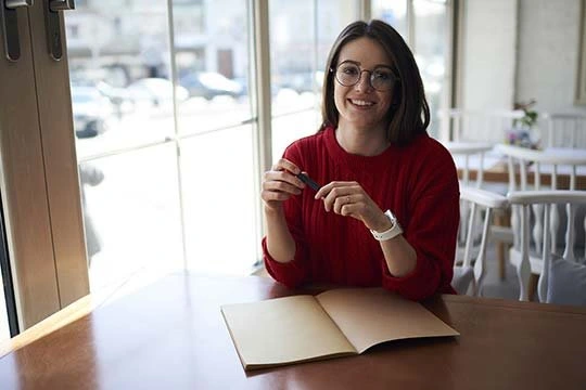 Frau am Schreibtisch sitzend mit einem Heft vor sich