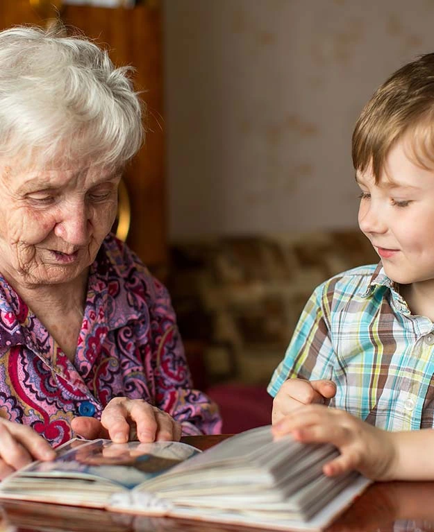 Alte Frau mit Kind am Tisch spielend