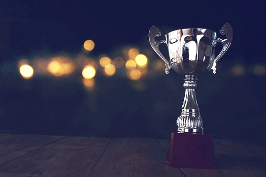 image of trophy over wooden table and dark background